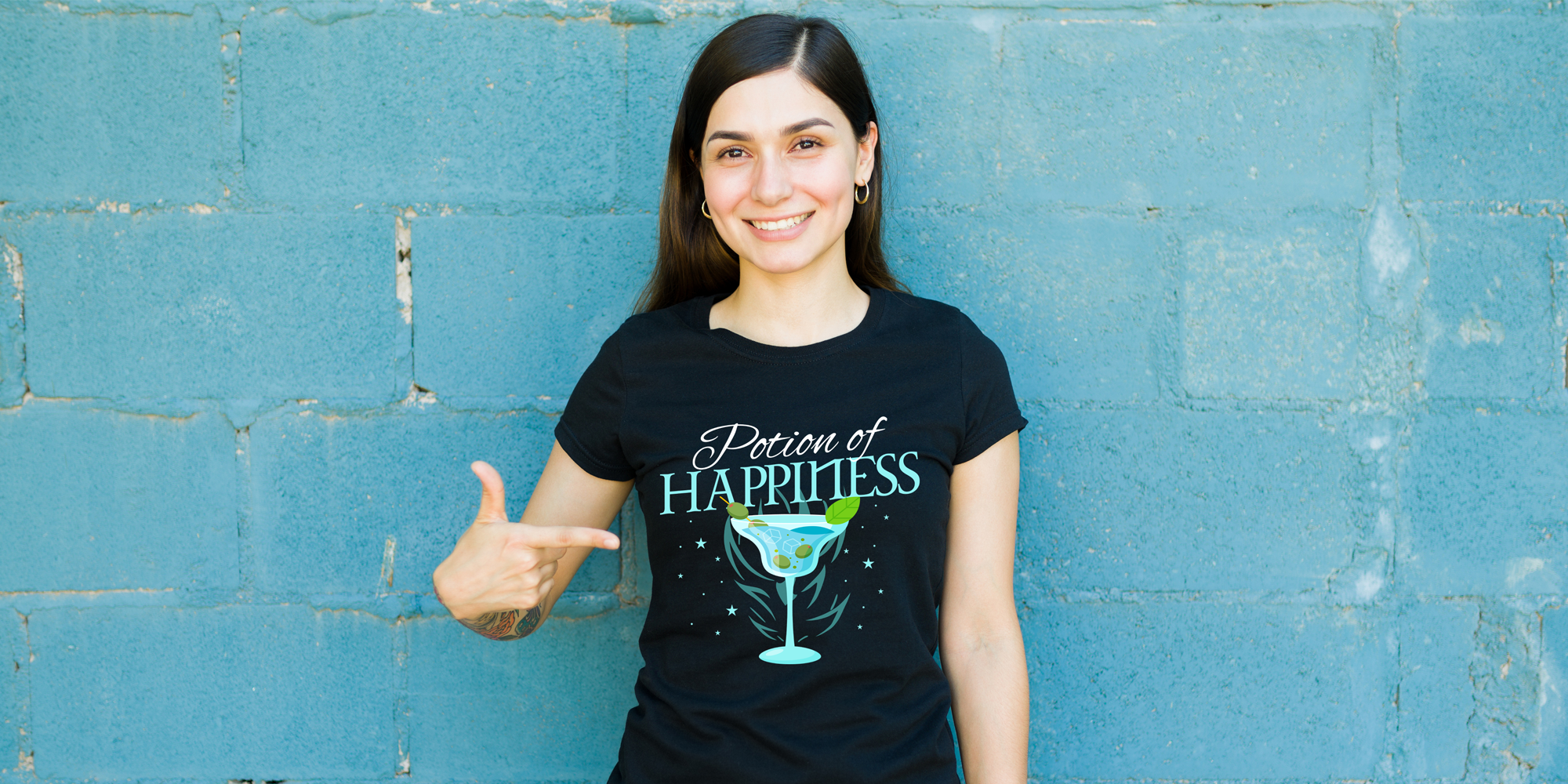 Female standing against a blue cinderblock wall pointing at her black t-shirt with a TTRPG-themed saying and artwork.
